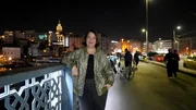 Phoebe Gaa steht auf einer der Brücken in Istanbul und schaut lächelnd in die Kamera. Im Hintergrund liegt die Stadt bei Nacht.
