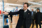 Holmes (Jonny Lee Miller, vorne) und Detective Bell (Jon Michael Hill, r.) untersuchen den Mord an einem als Comicheld maskierten Unbekannten. Von Eddie Eichhorn (Richard Portnow, 2.v.r.), dem Geschäftsführer eines Comicverlags, hoffen sie, die wahre Identität des Opfers zu erfahren ...