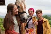 Lucy (Paulina Schnurrer, links) und Liam (Nils Hofschneider, rechts) sind superglücklich. Ihre Lieblings-Influencerin Tara Lovely (Carlotta Truman, Mitte) ist zu Besuch in Waldau.