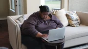 Kelly browses the computer while sitting on couch