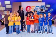 (v.li.): Kamerakind Jasper, das gelbe Rateteam aus Wien/Österreich, Zollbeamter Thomas Dyrda mit seinem Spürhund Idris, Elton, das rote Rateteam aus Athen/Griechenland, Piet Flosse und das blaue Rateteam aus München/Deutschland.