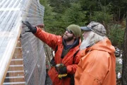 Matt Carlson shows his friend Gary Muehlberger a plastic wall he's put up for a new greenhouse on Gary's property.