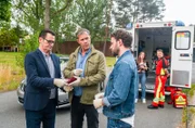 Am Tatort zeigen sich die beiden Ermittler Lars Englen (Ingo Naujoks, l.) und Finn Kiesewetter (Sven Martinek, 2.v.l.) sichtlich betroffen. Sie blicken zu Gregor (Jonas Minthe, r.), der ihnen ebenfalls bestürzt, das Alter des Mordopfers mitteilt.
