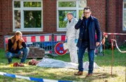 Der Krankenhausclown Fidan Petrov (Philipp Boos, liegend) liegt erschlagen im Hinterhof der Klinik. Die Kommissare Finn Kiesewetter (Sven Martinek, l.) und Lars Engel (Ingo Naujoks, r. mit Christoph Tomanek, 2.v.r.) ) finden heraus, dass der Tote ein Betrüger war.