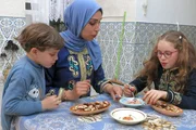Dhoha füllt mit ihren Kindern Datteln mit Pistazien- und Mandelpaste.
