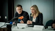 Thomas Jung (Johannes Zirner) und Caroline Seibert (Therese Hämer) beantworten die Fragen der Journalisten bei einer Pressekonferenz.