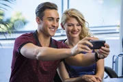 Chris (Taylor Glockner, li.) macht ein Foto mit der bekannten Autorin des Buches "Geheimnisse der Tiefe": Rikki Chadwick (Cariba Heine, re.).
