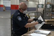Ein Kameramann filmt den CBP-Beamten Cisneros beim Öffnen eines gekennzeichneten Pakets auf der Suche nach versteckter Schmuggelware in der Poststelle des JFK International Airport in New York (National Geographic).
