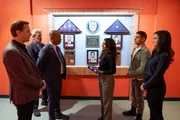 L-R: Special Agent Timothy McGee (Sean Murray), NCIS Director Leon Vance (Rocky Carroll), FBI Special Agent Alden Parker (Gary Cole), Diya Khatri (Menik Gooneratne), Special Agent Nicholas “Nick” Torres (Wilmer Valderrama), NCIS Special Agent Jessica Knight (Katrina Law)