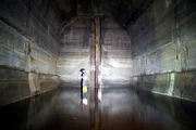 Ein Mitglied der Berliner Unterweltvereinigung wird von der 60 Fuß hohen Kammer dieses Test-U-Bahnhofs, einem der wenigen verbliebenen Überbleibsel von Hitler-Germania, in den Schatten gestellt.