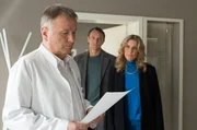 Verwaltungschefin Sarah Marquardt (Alexa Maria Surholt, re.) und der neue Klinikleiter Dr. Martin Stein (Bernhard Bettermann, mi.) teilen Dr. Roland Heilmann (Thomas Rühmann, li.) mit, dass sie ihn auf Schadensersatz verklagen. Roland hat im Alleingang ein sehr teures Medikament eingesetzt, für dessen Kosten die Krankenkasse nicht aufkommen wird. Nun klafft in den Kassen der Sachsenklinik ein 250.000 € großes Finanzloch.
