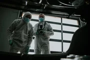 Zwei Detectives in forensischen Anzügen durchsuchen den Kofferraum.