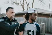 Polizist begleitet Mann zum Streifenwagen.