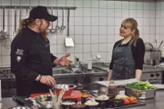 Lucki Maurer erklärt Anni Preuß welche Zutaten für die Burger benötigt werden.