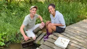 Pia und Michel kontrollieren eine Muschelkiste. Darin verbringen ausgewilderte Muscheln das erste Jahr, ehe sie direkt in den Bach dürfen.