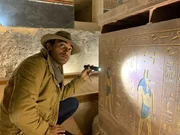 Ramy Romany looks at hieroglyphics with a flash light.