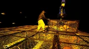 Nick Mavar, deckhand aboard the Northwestern, helps to stack pots.