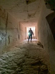 Ramy Romany walking down tomb hallway.