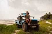 Press photo of Heino Dahmen sitting on his truck on the beach