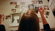 A portrait of Lori Orr-Kovach looking at old photos of her Dad John Orr.