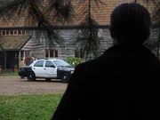 Jason watching the house from the bushes while police car is parked in front.