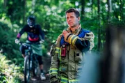 Ein Berufsfeuerwehrmann alarmiert das Mehrzweckfahrzeug (MTZ) zur Rettung eines gestürzten Downhill-Bikers.