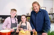Zusammen mit Lias und Malin Böhmer kocht Björn Freitag (r) leckere und kinderleichte Rezepte.