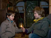 Sarah Marquardt hat ihrem Sohn Bastian (Johann Lukas Sickert, rechts) den Umgang mit dem Heilmann-Enkel Jonas (Anthony Petrifke) verboten. Doch die beiden Freunde lassen sich das nicht gefallen und hauen ab. In einem Bauwagen suchen sie bei Regenwetter Unterschlupf und schließen Blutsbrüderschaft.
