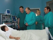 Prof. Simoni (Dieter Bellmann, 3. von rechts), Dr. Heilmann (Thomas Rühmann, 4. von rechts) und Dr. Globisch (andrea Kathrin Loewig, 2. von rechts) freuen sich, dass Chenoas (Chenoa Shepard, links) Operation so erfolgreich war. Chenoa hingegen wundert sich über so viele Ärzte an seinem Bett und auch Dr. Weimar (Peter von Strombeck, rechts) kann diese überschwängliche Freude nur wenig teilen, wenn er an die vielen anderen Kinder in Mosambik denkt.