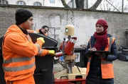 Tarik (Daniel Rodic, li.) und Ralle (Jörn Hentschel) im Einsatz mit Robo-Kollegin „Dörte. Projektleiterin Dr. Hanna Keller (Inez Bjørg David) verfolgt genau jeden Handgriff.