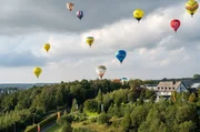 Es ist ein Ballonfestival der Extraklasse. Seit 1986 treffen sich begeisterte Ballonfahrer im Sauerland zur "Warsteiner Internationale Montgolfiade". - Nordrhein-Westfalen, Warstein: Ballons fliegen nach dem ersten Massenstart bei der 30. Warsteiner Internationalen Montgolfiade am Samstag über der Landschaft.