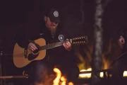 Lucki spielt Gitarre am Lagerfeuer.
