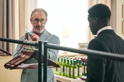 Jaheim (Josh Tedeku, r.) braucht dringend einen Job und wird von Alan (Alan Cumming, l.) für eine Geburtstagsparty engagiert. Dort soll er sich um die Garderobe der Gäste kümmern.