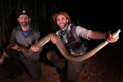 Mario and Coyote hold up a large python.