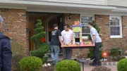 Maurizio, Buddy Valastro, and Anthony carry elevator cake into house.Maurizio, Buddy, and Anthony carry the elevator cake into a house.