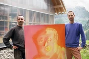 Kulturplatz Neues Alp-Leben - Retten Kunst und Musik ein Bergdorf? Florian Maritz präsentiert «Kulturplatz»-Host Nino Gadient (rechts) sein gemaltes Kunstwerk auf der Alp Gitschenen vor einer Bergkulisse.
