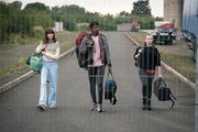 Bea (Aoife Hughes, r.) ist mit Alice (Scarlett Rayner, l.) und Finn (Jordan Adene, M.) in die Stadt gefahren. Dort will sie nach ihren Freunden suchen. Sie will zum Sitz der Umweltorganisation, der Fischer und seine Leute angehören.