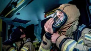 Feuerwehrleute der Berufsfeuerwehr Heidelberg legen eine Atemschutzmaske an.