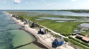 Auf Tuchfühlung mit dem Meer: Die Strandvillen-Eigentümer vom Graswarder leben in ständiger Sorge, dass sich die Ostsee wieder ein Stück Land holt – die Holzbuhnen im Wasser sollen das verhindern.