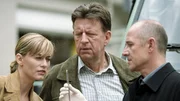 Am Mantel der Toten entdeckt Dr. Robert Kolmaar (Ulrich Mühe, r.) Maden, die er im Labor analysieren will. Judith Sommer (Gesine Cukrowski, l.) und Joe Hoffer (Jörg Gudzuhn, M.) schauen sich ebenfalls die Made genauer an.