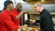 Chef Robert Irvine shows Darnell Morgan and David Wilmott, owners of Forks & Flavors, how to make the entrées from the new menu for the restaurant in Kennesaw, GA, as seen on Restaurant: Impossible, Season 20.