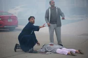 Zwei Männer helfen einer verletzten Person.