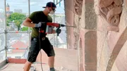 Am Südgiebel des Querhauses stemmt Steinmetz Manuel Heininger ein Stück beschädigten Sandstein aus der Wand, da es ersetzt werden muss.