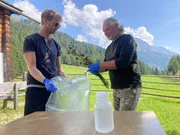 Dr. Martin Tribsch (r.) und Matthias Hopfinger geben Blumen in Plastiksack