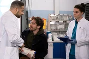 Matteo (Mike Adler, l.) ist wieder zurück am JTK und behandelt gemeinsam mit Tom (Tilman Pörzgen, r.) den Patienten Robert Müller (Nico Rogner, M.). Er hat nach einem Unfall mit einem Fahrradkurier Verletzungen am Auge, Arm und Finger.