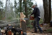 Action shot of Marty Raney carving a moose out of a log using a chain saw.