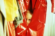 Lotta (Grete Havnesköld) versteckt sich im Regenmantel, um ihren Vater zu überraschen.