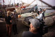 Crew films Mariana van Zeller as she interviews masked man.