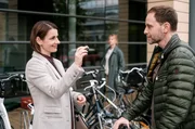 Maria Weber (Annett Renneberg, li.) freut sich über einen Glücksbringer, den ihr Kai Hoffmann (Julian Weigend, re.) heimlich in die Tasche gesteckt hat. Dabei werden die beiden von Kais Ex-Frau Ina Schulte (Isabell Gerschke, mi. hi.) beobachtet.