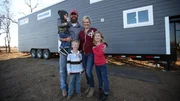 The Johnson family poses in front of their house smiling at the camera, for Ty and Taylor's build, in Enid, Oklahoma, as seen on Tiny House, Big Living.
